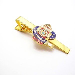 May include: Gold-toned tie clip with a decorative emblem. The emblem features red, blue, and white enamel with the text "STATE COMMANDER JIM" and "NY 92-93". The clip is on a white background.