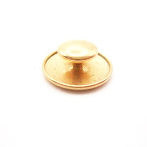 May include: A gold-colored collar stud with a round, flat base and a small, rounded top. The stud is set against a white background, highlighting its metallic sheen. This accessory is likely used for formal shirts or blouses.