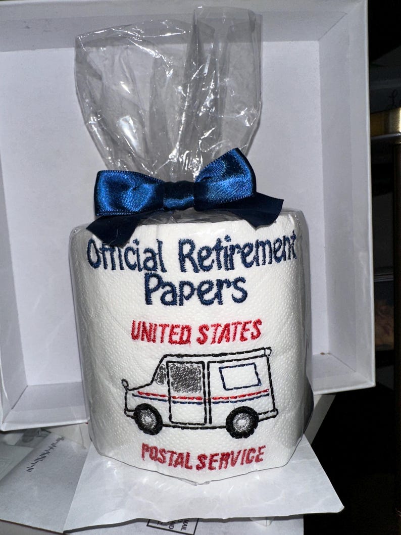 Pu&ograve; includere: Un rotolo di carta igienica bianca con le parole "Official Retirement Papers" ricamate in blu. Le parole "United States Postal Service" e un camion postale sono ricamate in rosso e nero. Il rotolo &egrave; avvolto in cellophane e legato con un fiocco blu.