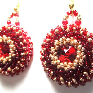 May include: A pair of red and gold beaded earrings with a red crystal in the center of each earring.
