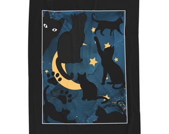 May include: A black and white blanket featuring a celestial design with black cat silhouettes, yellow stars, and a crescent moon against a dark blue background. The blanket has a black border and a white inner frame.