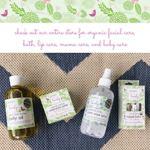 May include: An assortment of organic baby care products, including belly oil, calendula salve, cloth wipe spray, and nipple balm, are displayed on a patterned surface. The products are branded "green + lovely" and feature botanical designs.