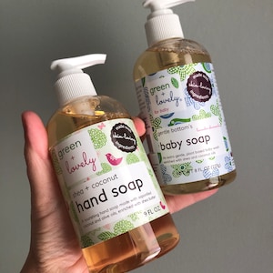 May include: Two clear plastic bottles of Green + Lovely hand and baby soap. The hand soap is shea and coconut scented, 266 ml. The baby soap is 237 ml. Both bottles have white pump dispensers and labels with green floral designs.