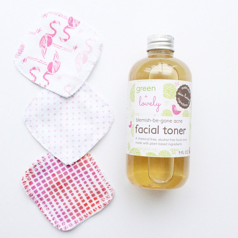 May include: A clear bottle of facial toner with a silver cap and a label that reads "green + lovely blemish-be-gone acne facial toner." Three reusable facial pads with pink patterns are next to the bottle. The bottle contains 9 fl oz of toner.