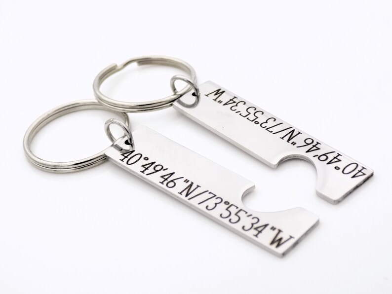May include: Two silver keychains with engraved coordinates, 40&deg;49&prime;46&Prime;N/73&deg;55&prime;34&Prime;W, that fit together to form a heart shape.