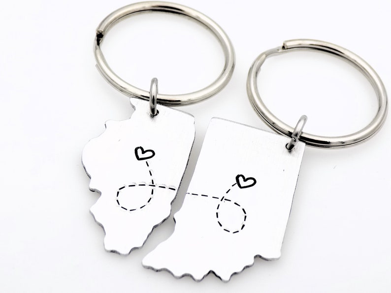 May include: Two silver keyrings with a heart and a dotted line connecting the outlines of the states of Illinois and Indiana.