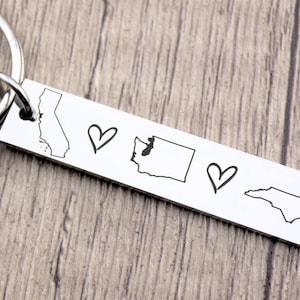 May include: Silver keychain with outlines of California, Washington, and North Carolina states, separated by hearts.