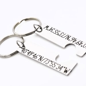 May include: Two silver keychains with matching coordinates engraved on them. The coordinates are 40&deg;49&prime;46&Prime;N/73&deg;55&prime;34&Prime;W and 40&deg;49&prime;46&Prime;N/73&deg;55&prime;34&Prime;W. The keychains are designed to fit together like puzzle pieces.