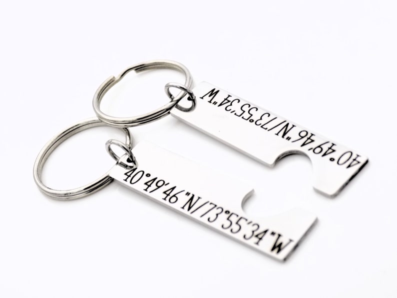 May include: Two silver keychains with matching coordinates engraved on them. The coordinates are 40&deg;49&prime;46&Prime;N/73&deg;55&prime;34&Prime;W and 40&deg;49&prime;46&Prime;N/73&deg;55&prime;34&Prime;W. The keychains are designed to fit together like puzzle pieces.