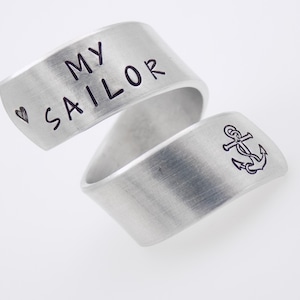 K&ouml;nnte beinhalten: Zwei silberfarbene Ringe. Auf einem Ring steht "MY SAILOR" und ein Herzsymbol. Der andere Ring zeigt ein Ankersymbol. Die Ringe sind gebogen und haben ein geb&uuml;rstetes Metall-Finish.