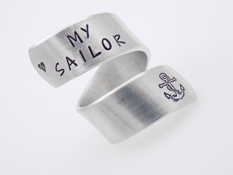 K&ouml;nnte beinhalten: Zwei silberfarbene Ringe. Auf einem Ring steht "MY SAILOR" und ein Herzsymbol. Der andere Ring zeigt ein Ankersymbol. Die Ringe sind gebogen und haben ein geb&uuml;rstetes Metall-Finish.