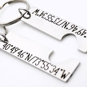 May include: Two silver keychains with engraved coordinates. The top keychain has the coordinates 40&deg;49&prime;46&Prime;N/73&deg;55'34"W. The bottom keychain has the coordinates 40&deg;49&prime;46&Prime;N/73&deg;55&prime;34&Prime;W.