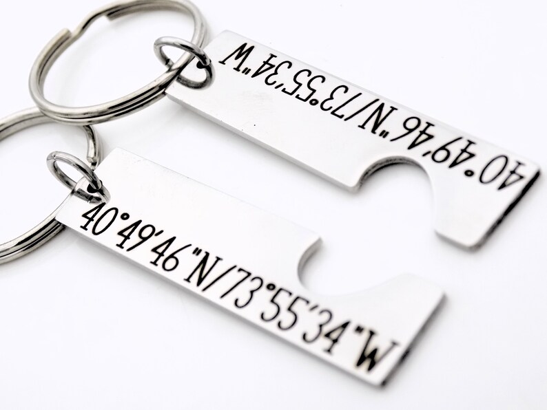 May include: Two silver keychains with engraved coordinates. The top keychain has the coordinates 40&deg;49&prime;46&Prime;N/73&deg;55'34"W. The bottom keychain has the coordinates 40&deg;49&prime;46&Prime;N/73&deg;55&prime;34&Prime;W.