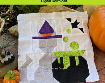 Könnte beinhalten: Ein Quiltblockmuster mit einer grauen Katze, die einen lila und orangefarbenen Hexenhut trägt, neben einem schwarzen Kessel mit grüner, sprudelnder Flüssigkeit sitzt. Der Block ist 12,5 Zoll mal 12,5 Zoll unfertig und 12 Zoll mal 12 Zoll fertig. Das Muster heißt "Cauldron Cat Quilt Block Pattern" und ist ein digitaler Download von Fierce Fantasy Designs.