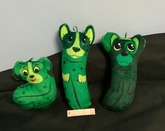 Könnte beinhalten: Drei grüne Plüsch-Hunde-Spielzeuge. Die Hunde sind in verschiedenen Posen und haben schwarze Augen und Nasen. Die Spielzeuge sind aus weichem, plüschigen Stoff und für Kinder geeignet.