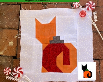 Könnte beinhalten: Ein Quiltblockmuster mit einer Katze mit einem Ornament in Form eines Kürbisses. Das Muster ist 10-1/2 Zoll mal 10-1/2 Zoll unfertig und 10 Zoll mal 10 Zoll fertig. Das Muster kann auch für Halloween verwendet werden, indem die Stofffarben geändert werden.