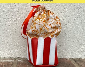 Könnte beinhalten: Ein PDF-Schnittmuster für eine Popcorn-Tasche mit Kordelzug in rot-weiß gestreiftem Design. Das Schnittmuster ist für eine Kordelzugtasche mit einer Höhe von 25,4 cm, einer Breite von 10,2 cm und einer Tiefe von 10,2 cm.
