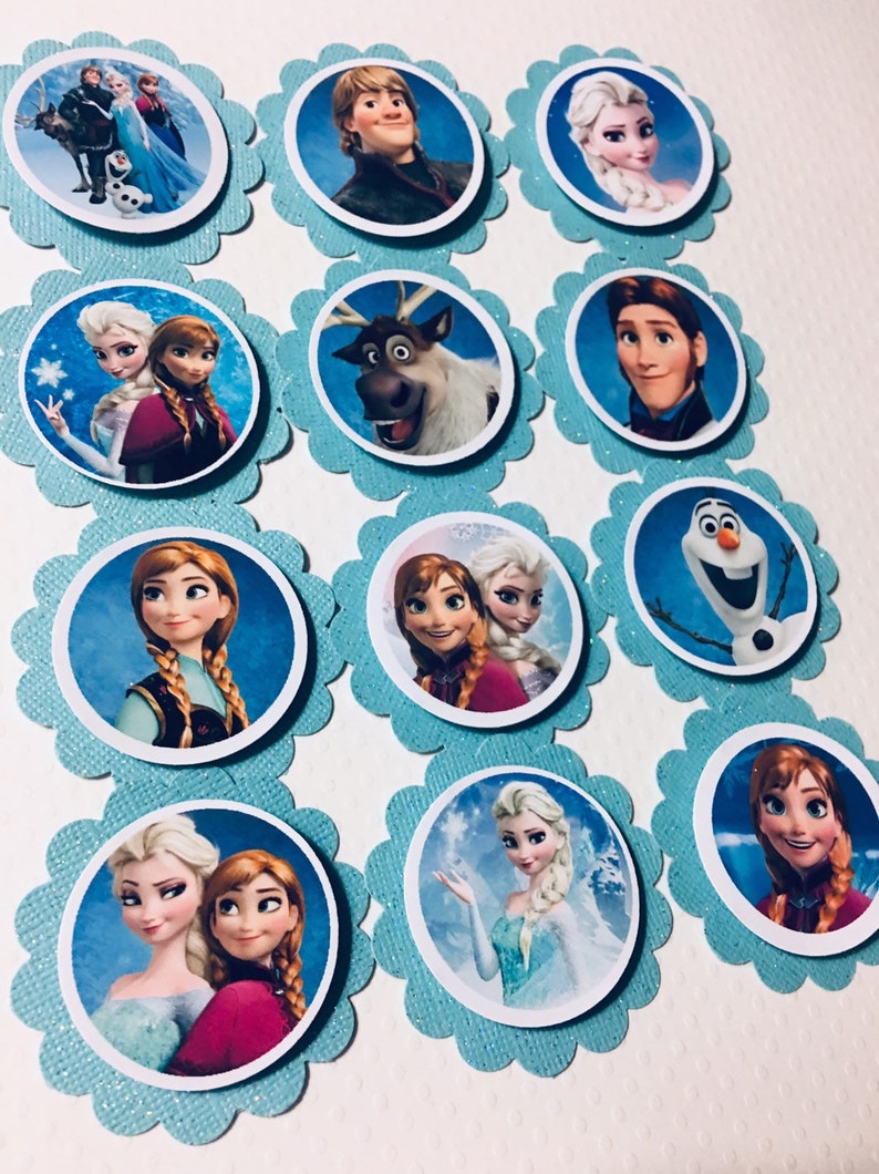 Puede incluir: Doce adornos redondos para cupcakes con personajes de la pel&iacute;cula animada Frozen. Los adornos est&aacute;n impresos en papel blanco y tienen un fondo azul con purpurina. Los personajes incluyen a Elsa, Anna, Kristoff, Olaf, Sven y Hans.