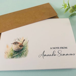 May include: A white card with a brown envelope. The card has a watercolor illustration of a brown bird sitting in green grass. The text "A Note From Amanda Simmons" is printed in black at the bottom of the card.