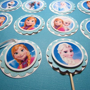 Puede incluir: Un conjunto de 10 adornos redondos para cupcakes con personajes de la pel&iacute;cula animada Frozen. Los adornos est&aacute;n impresos en cartulina blanca con un borde azul brillante y presentan im&aacute;genes de Elsa, Anna, Olaf y Kristoff.