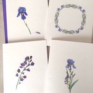 May include: Four blank cards with watercolor illustrations of purple iris flowers and lavender. The cards are perfect for sending a handwritten note or creating a unique piece of art.