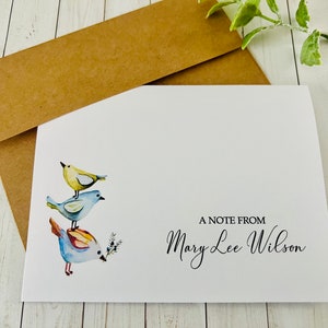 May include: A white card with a watercolor illustration of three blue and yellow birds stacked on top of each other. The card has the text "A Note From Mary Lee Wilson" printed on the bottom right corner.