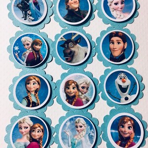 Puede incluir: Doce adornos redondos para cupcakes con personajes de la pel&iacute;cula animada Frozen. Los adornos est&aacute;n impresos en papel blanco y tienen un fondo azul con purpurina. Los personajes incluyen a Elsa, Anna, Kristoff, Olaf, Sven y Hans.