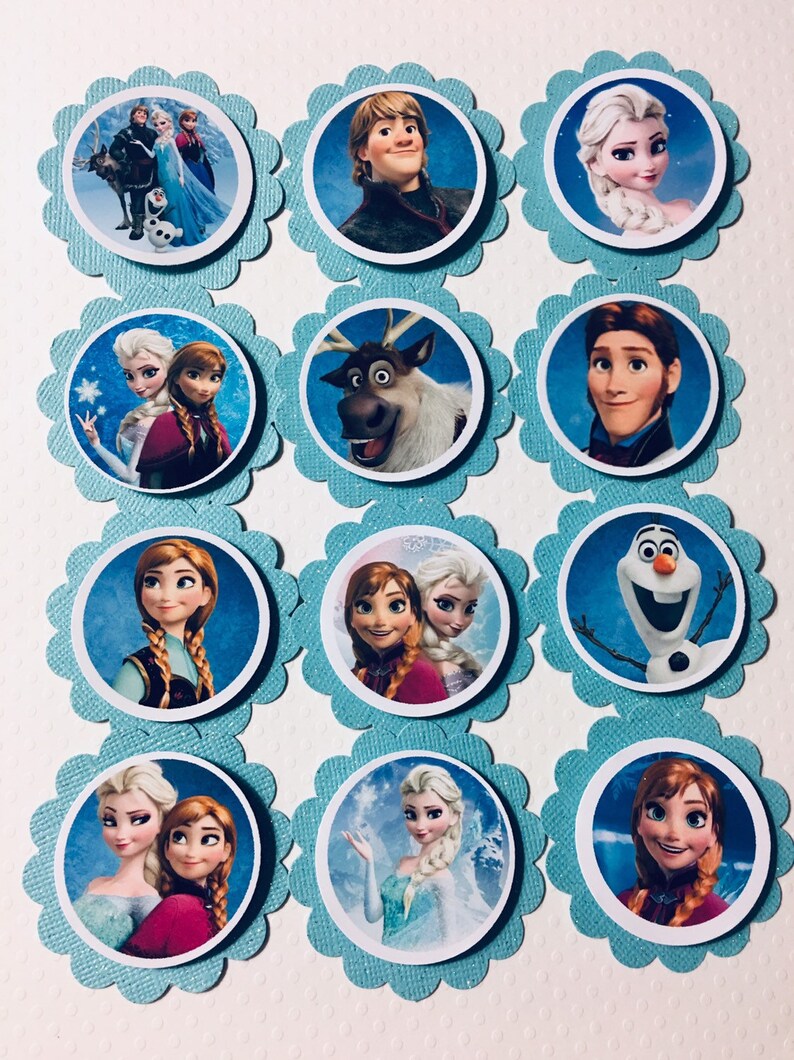 Puede incluir: Doce adornos redondos para cupcakes con personajes de la pel&iacute;cula animada Frozen. Los adornos est&aacute;n impresos en papel blanco y tienen un fondo azul con purpurina. Los personajes incluyen a Elsa, Anna, Kristoff, Olaf, Sven y Hans.