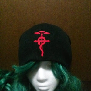 May include: Black beanie with a red embroidered symbol of a cross with a circle and wings.