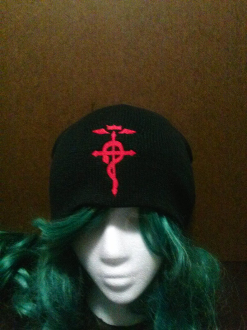 May include: Black beanie with a red embroidered symbol of a cross with a circle and wings.