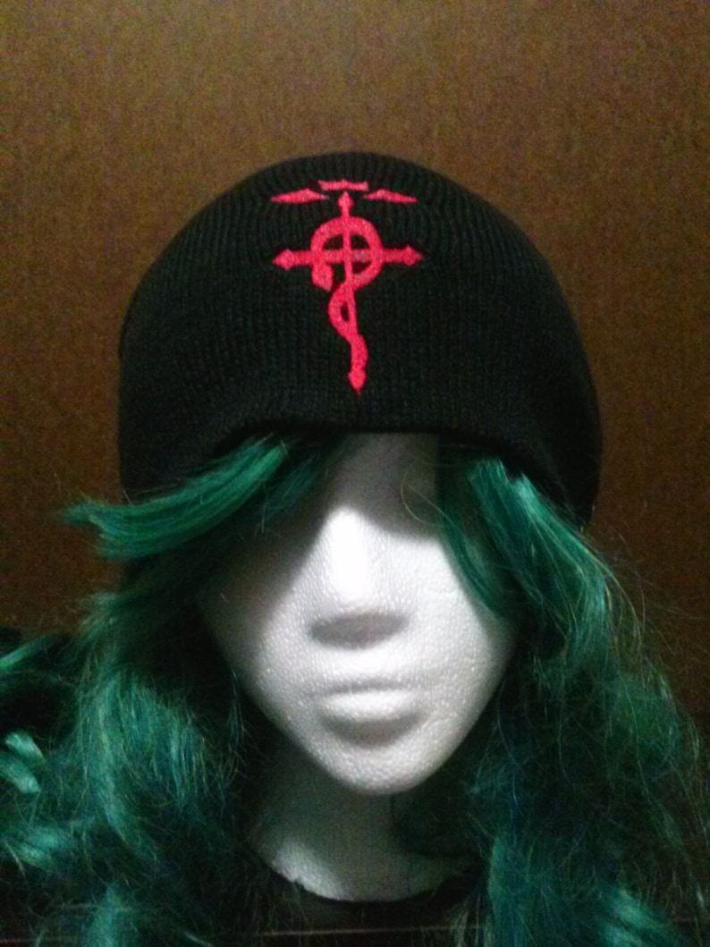 May include: Black beanie with a red embroidered symbol, resembling a cross with a snake wrapped around it.
