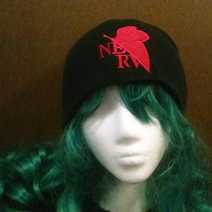 May include: Black beanie with a red and white "NERV" logo and a red leaf design.