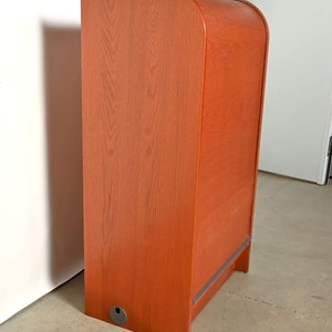 May include: A wooden cabinet with a rounded top and a single door. The cabinet is a reddish-brown color and has a small, round hole on the bottom.