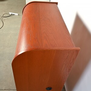 May include: A wooden roll top desk with a rich brown finish. The desk has a curved top and a single drawer.