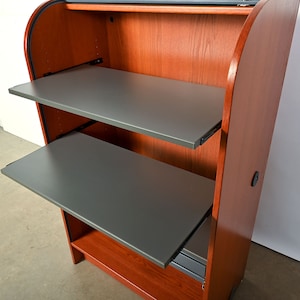 May include: A wooden cabinet with two pull-out shelves. The shelves are gray and the cabinet is a reddish-brown color.