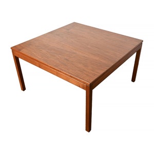 May include: A square wooden coffee table with a light brown finish and simple, straight legs.