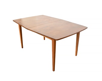 Puede incluir: Una mesa de comedor de madera con una tapa rectangular y cuatro patas. La mesa tiene un acabado marrón claro y un diseño sencillo.