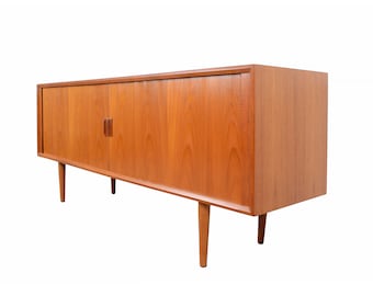 May include: A mid-century modern wooden sideboard in a warm, reddish-brown hue. The cabinet has two doors with small, vertical wooden handles and tapered legs. The design is simple and elegant, suitable for various interior styles. The sideboard is approximately 180 cm long.