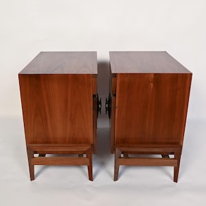 Puede incluir: Dos mesitas de noche de madera a juego con un acabado marr&oacute;n c&aacute;lido. Cada mesita tiene una parte superior rectangular, un solo caj&oacute;n y un estante inferior sostenido por cuatro patas. Las mesitas est&aacute;n una al lado de la otra.