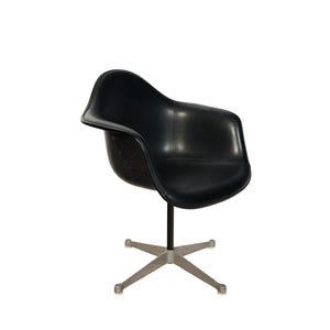 May include: Black swivel chair with a molded seat and armrests. The chair has a black seat and back, a black stem, and a silver-colored, five-star base. The chair is designed for comfort and style.