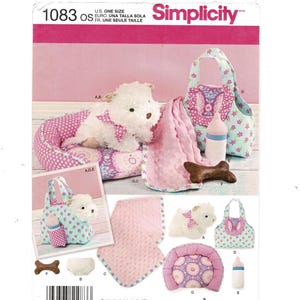 May include: Simplicity pattern 1083 for pet accessories including a plush white dog, a pink polka dot bed, a light blue floral tote bag, a pink textured blanket, a brown bone toy, and a bottle. The pattern features instructions for these items.