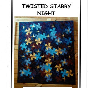 May include: A quilt with a dark blue background and a pattern of gold, light blue, and maroon star-like shapes. The quilt is labeled "Twisted Starry Night" in large, bold, black letters at the top.