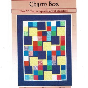 May include: A colorful quilt pattern with the text "Charm Box" at the top. The quilt design features a patchwork of squares in various colors, including yellow, red, blue, and green, set against a dark blue border. The text "Uses 5" Charm Squares or Fat Quarters!" is also visible.