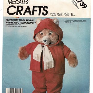 May include: McCall's Crafts pattern 2739 for a Teddy Ruxpin bear outfit. The package features a brown teddy bear wearing a red hooded jacket, matching red pants, and a white fringed scarf. The text includes Travel with Teddy Ruxpin.