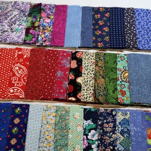 May include: A collection of fabric squares in various colors and patterns. The fabrics include floral, paisley, and solid designs in shades of blue, red, green, and purple. Ideal for quilting or crafting projects.