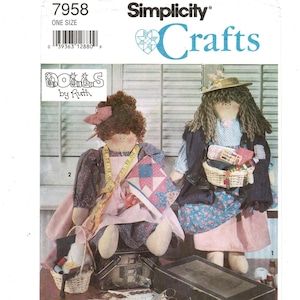 May include: A Simplicity Crafts pattern featuring two handmade dolls. The doll on the left wears a pink apron, a measuring tape, and holds a quilt. The doll on the right wears a hat and carries a basket. The pattern is labeled "Dolls by Ruth."