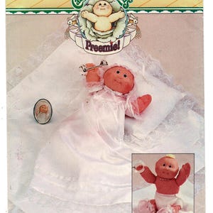 May include: A Cabbage Patch Kids Preemie doll sewing pattern package 3387. The cover features a doll in a white gown and bonnet, a small oval portrait, and an inset showing a doll in a diaper and booties. The text reads Cabbage Patch Kids Preemie.
