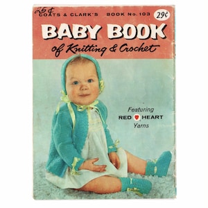 May include: Vintage "Baby Book of Knitting & Crochet" book cover. The cover features a baby in a blue knitted outfit and bonnet. The book's title is in large white letters on a red background. The book also features Red Heart Yarns.