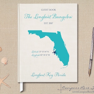 May include: A white guest book with a teal map of Florida and the text "The Longboat Bungalow Est. 2017" and "Longboat Key, Florida".