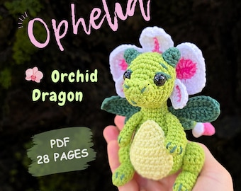 May include: A crochet amigurumi dragon with light green skin, a pale yellow belly, and dark green wings. The dragon features a large white and pink orchid flower on its head. Text on the image reads: Ophelia, Orchid Dragon, PDF 28 PAGES, English (US), CODENAME_BUTTERFLY.